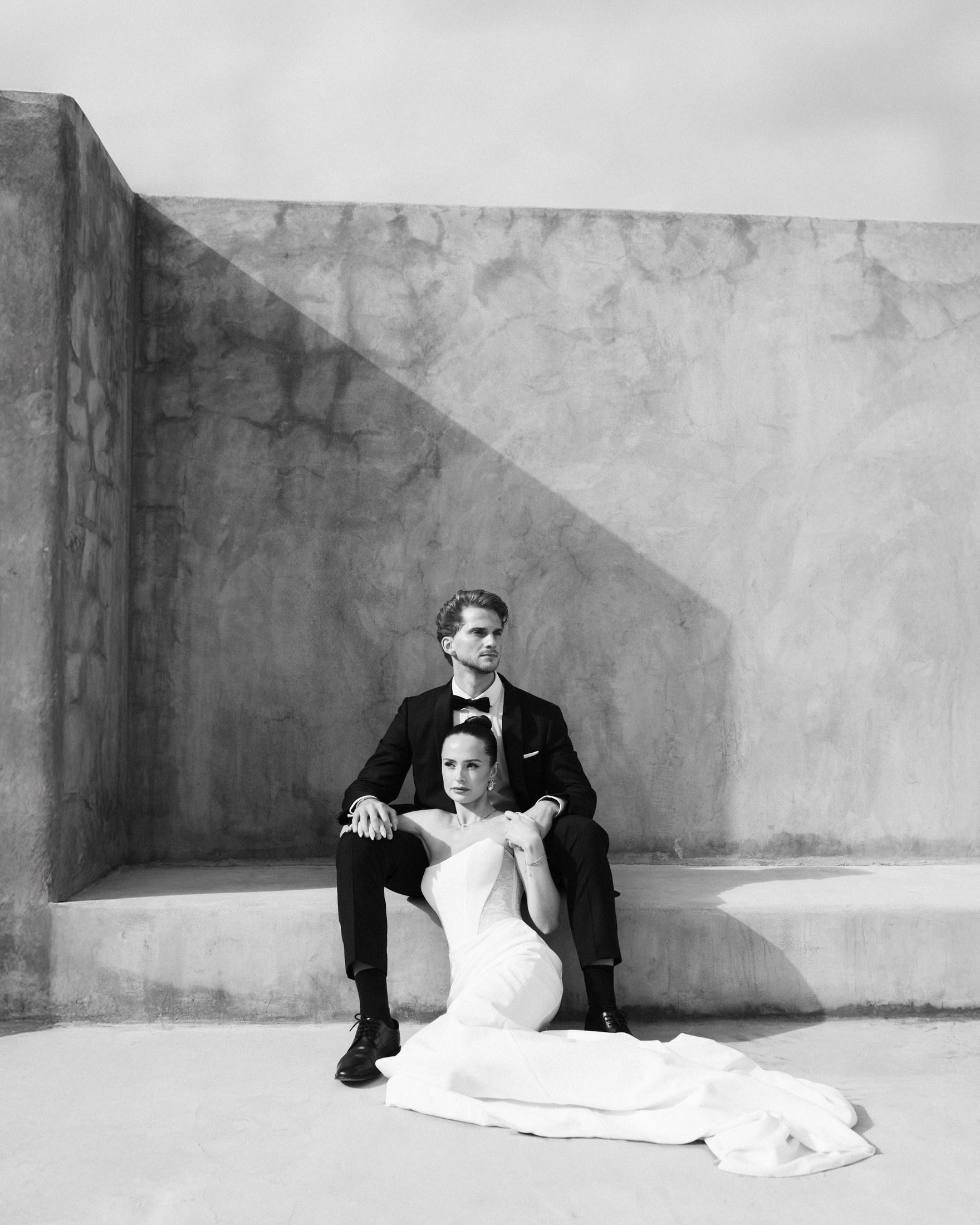 Couple sitting in front of a concrete wall on Mykonos, black and white