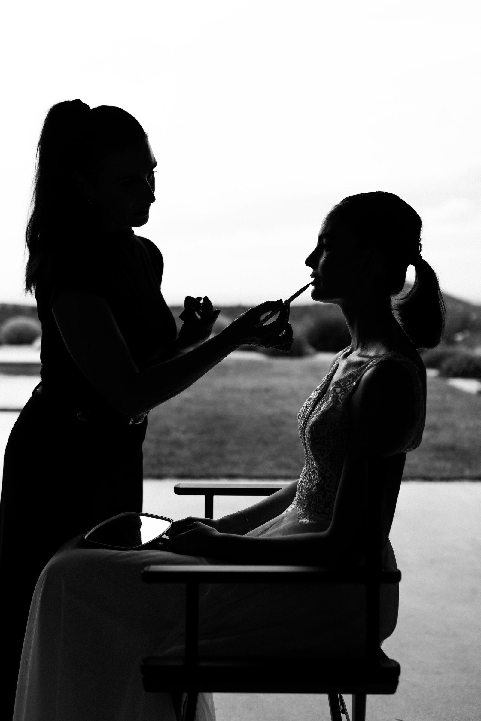 Silhouette der Visagistin, die der Braut das Make-up macht