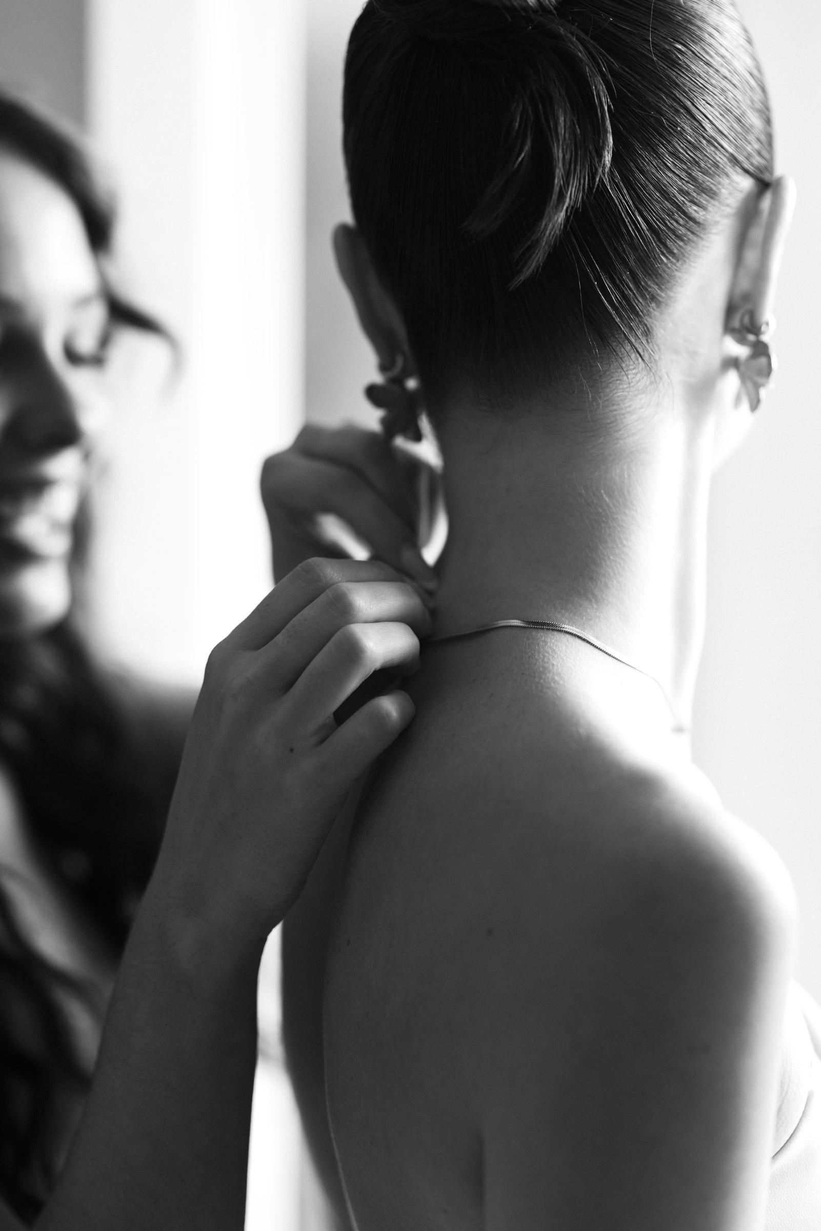 Details beim Getting Ready: die Braut richtet ihren Schmuck, Schwarzweiß