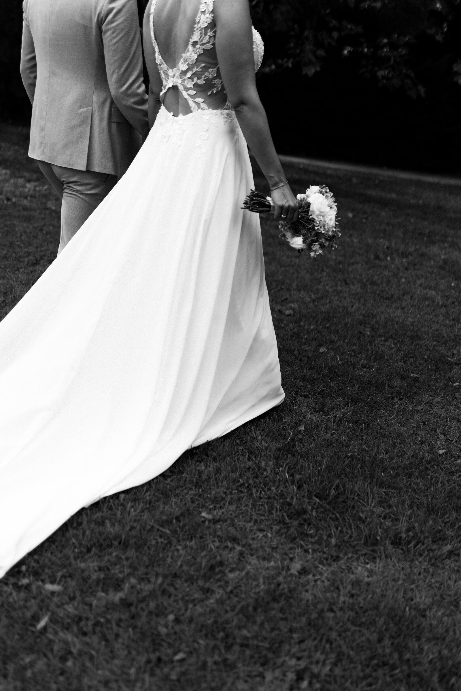 Bride from behind with a long train on a meadow, black and white