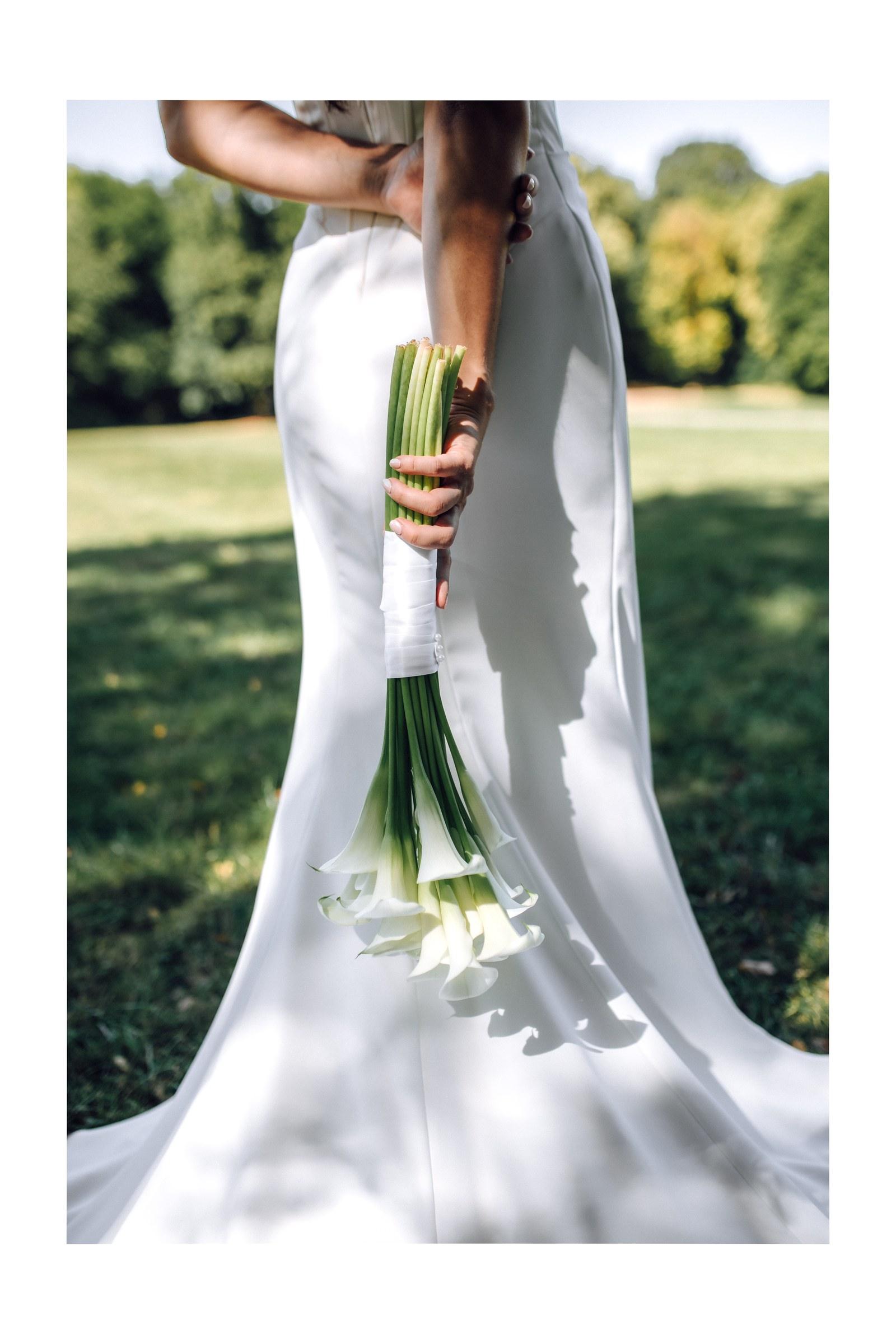 Die Braut hält den Strauß aus Calla hinter dem Rücken