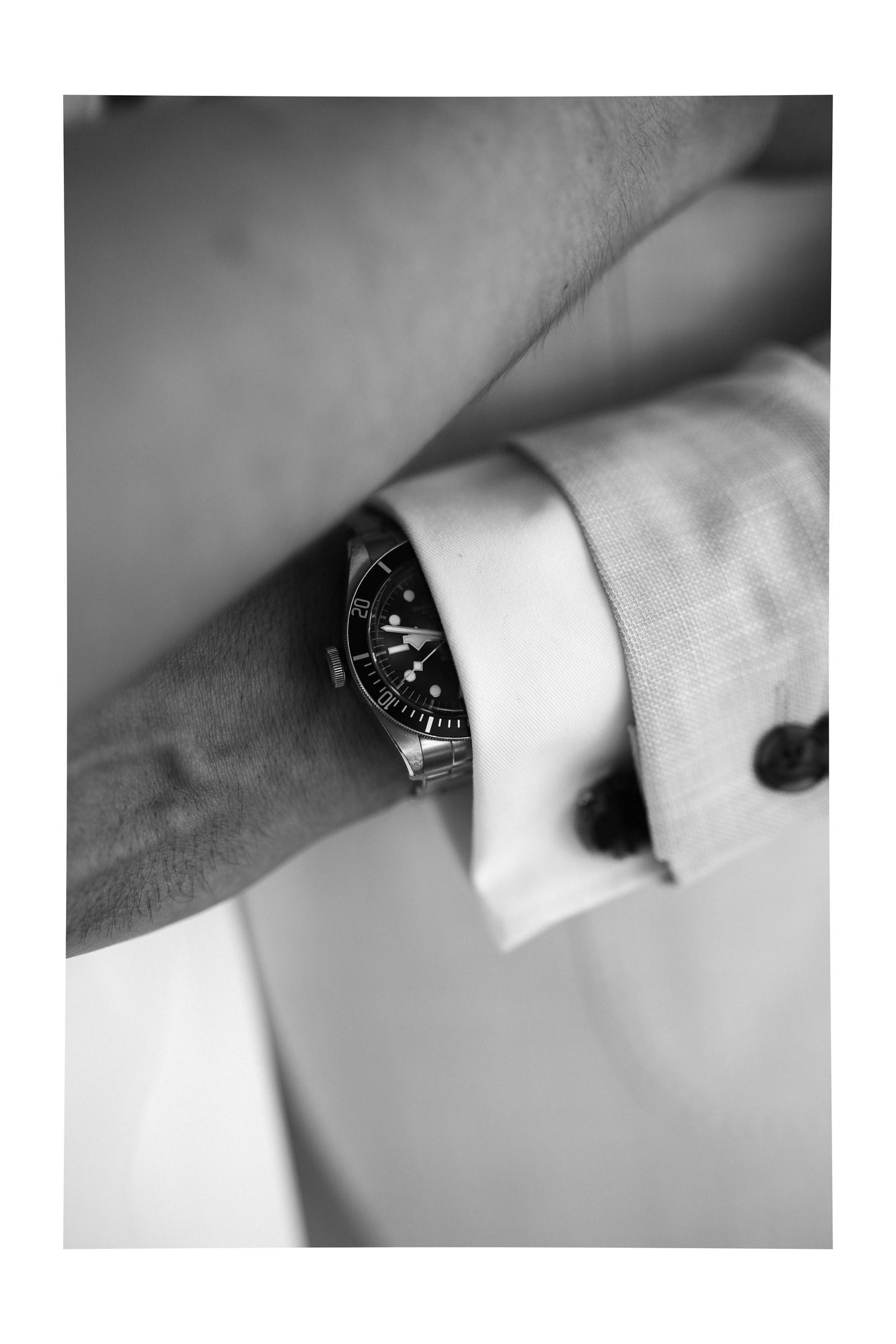 Detail: Armbanduhr und Manschettenknopf am hellen Anzug, Schwarzweiß