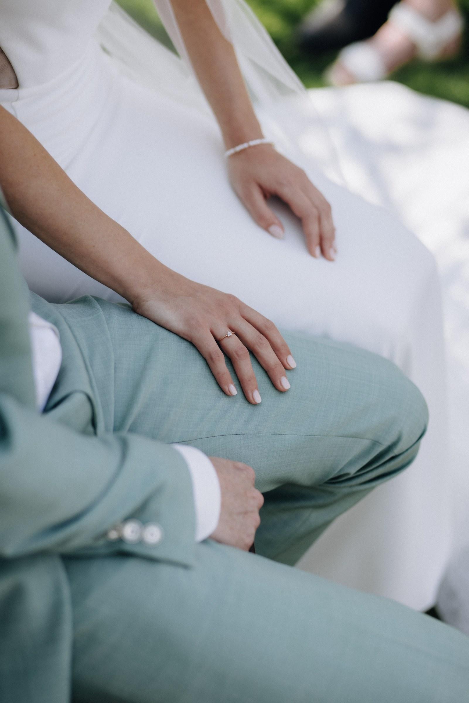 Die Hände von Celine und Philipp während der Trauung, auf dem mintgrünen Anzug